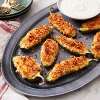 A platter of jalapeno poppers with a small bowl of dip.
