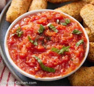 Pinterest graphic of a bowl of marinara sauce topped with ribboned basil along with some mozzarella sticks.