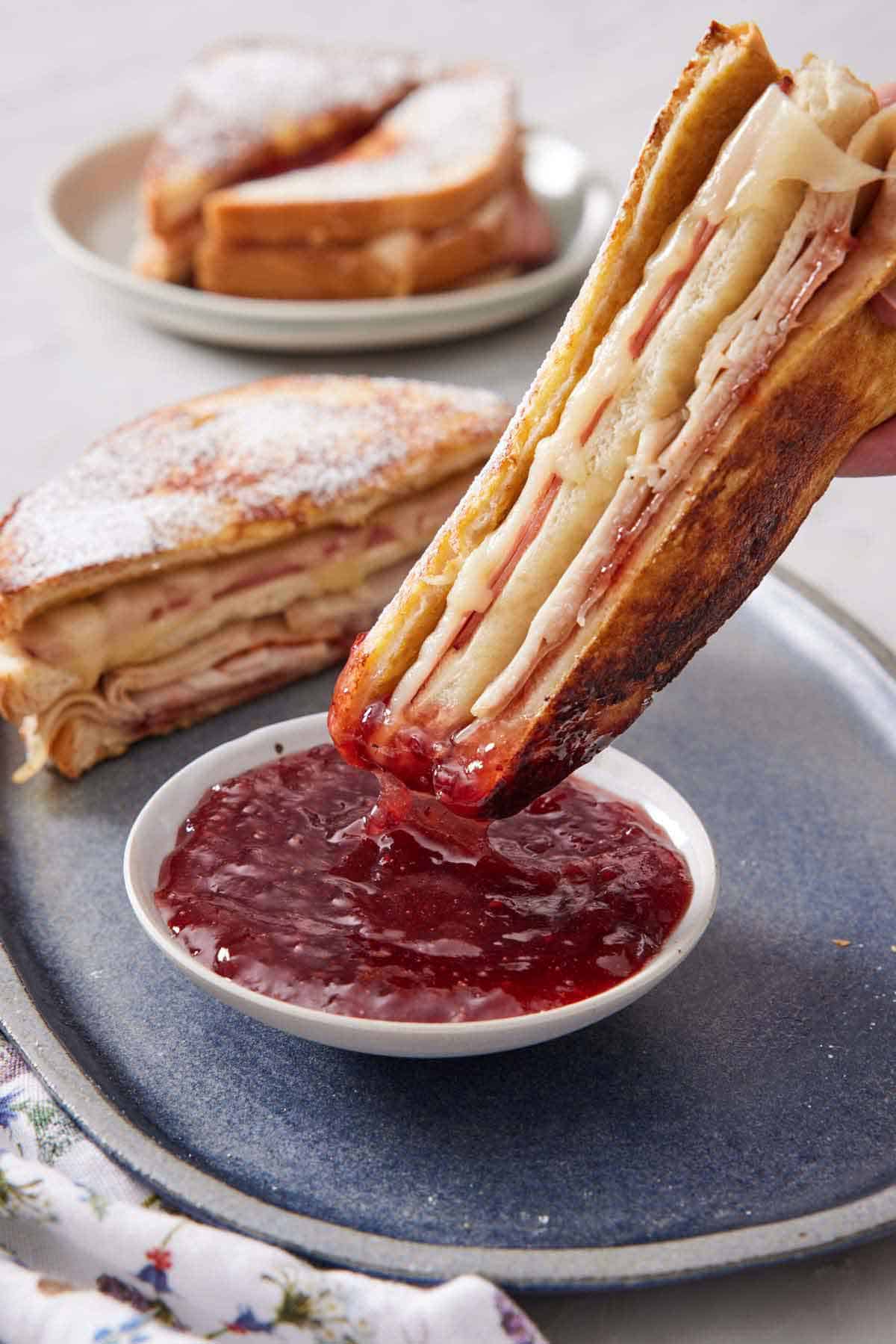 Half of a Monte Cristo sandwich dipped into a bowl of jam.