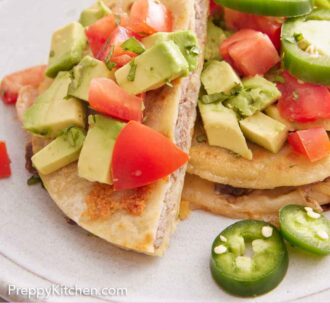 Pinterest graphic of a plate with a mulita cut in half, with one half leaning on the other. Topped with avocados, tomatoes, and jalapenos.
