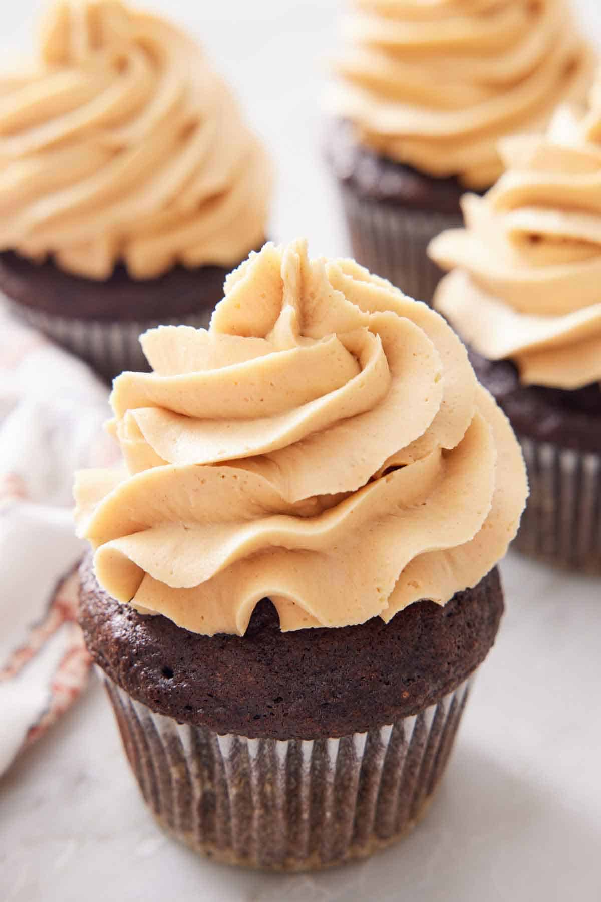 A chocolate cupcake with peanut butter frosting on top with more in the background.
