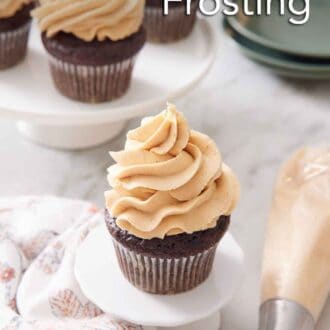 Pinterest graphic of a cupcake with peanut butter frosting on top with more frosted cupcakes in the background. A piping bag and plates off to the side.