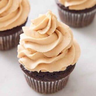 A slightly overhead angled view of peanut butter frosting on top of a chocolate cupcake.