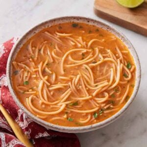 A bowl of sopa de fideo with a spoon beside it.