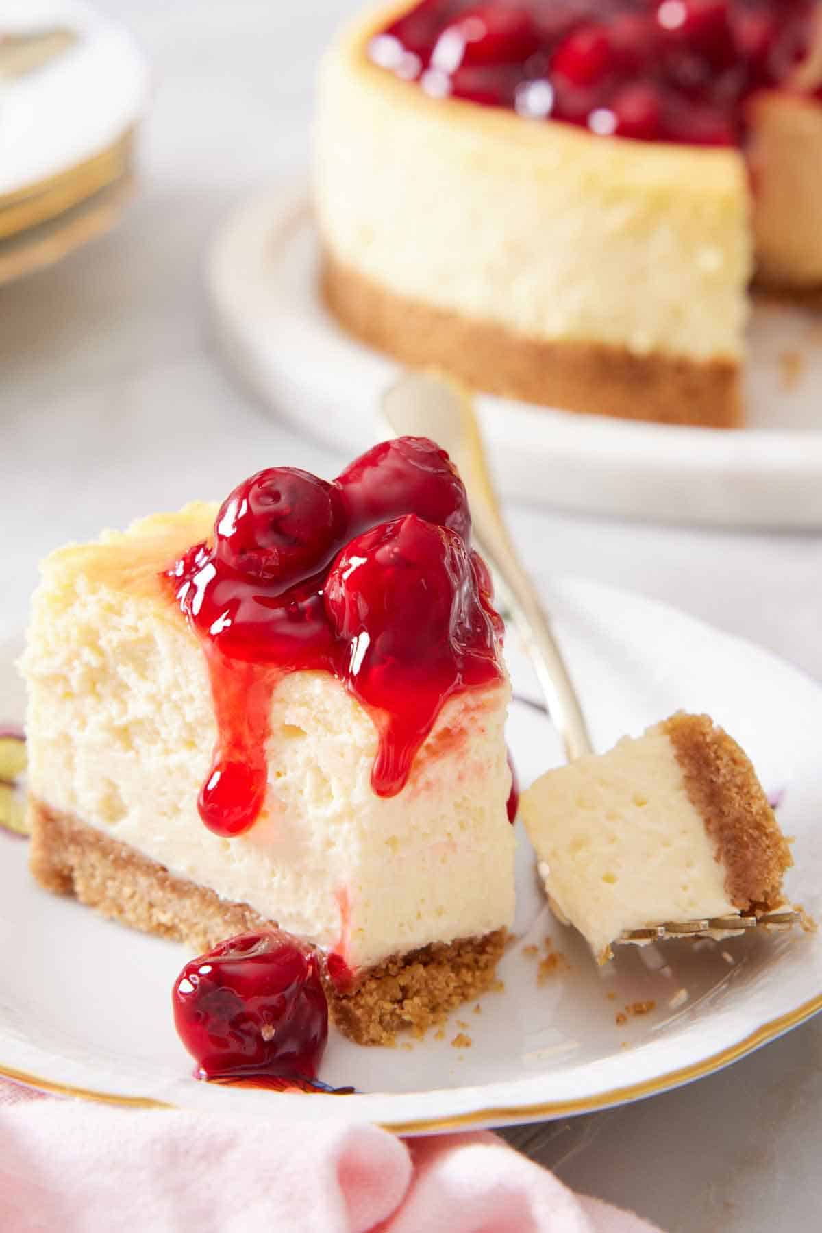 A slice of air fryer cheesecake on a cake with the tip scooped onto a fork beside it on the cake.