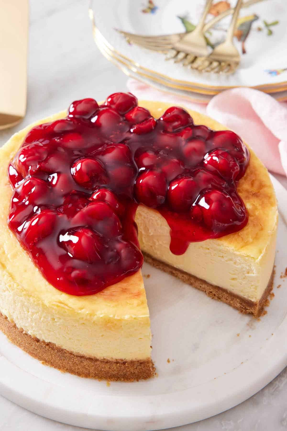 An air fryer cheesecake topped with a cherry sauce with a slice cut out.