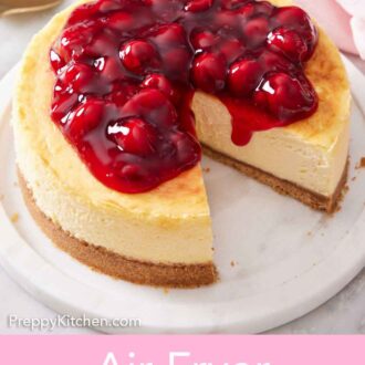 Pinterest graphic of an air fryer cheesecake topped with a cherry sauce with a slice cut out.