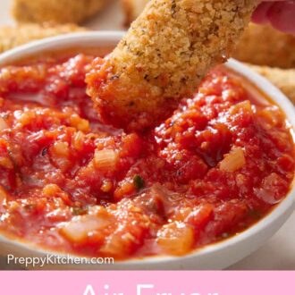 Pinterest graphic of an air fryer mozzarella stick dipped into a bowl of marinara sauce.