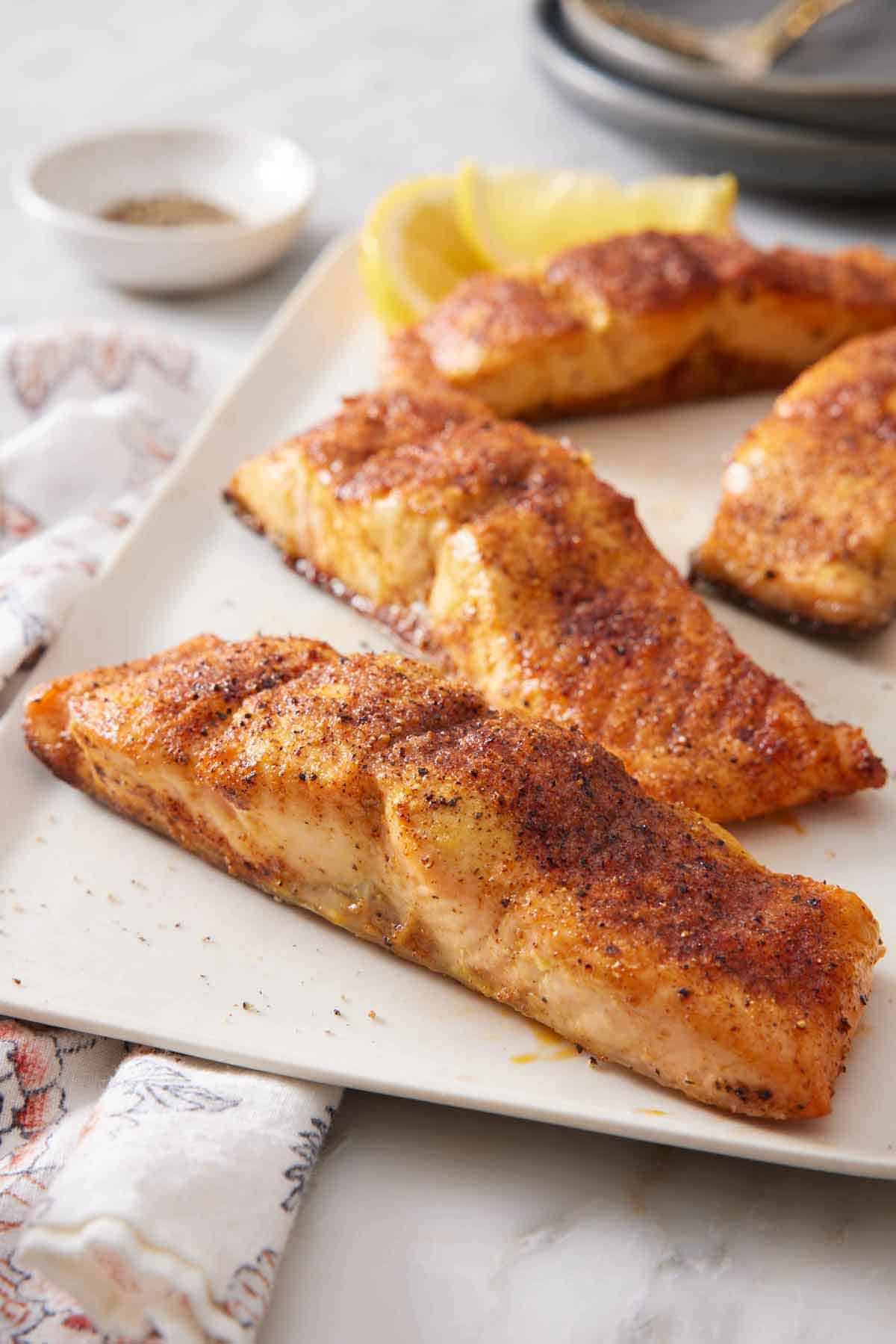 A platter with air fryer salmon with lemon wedges.