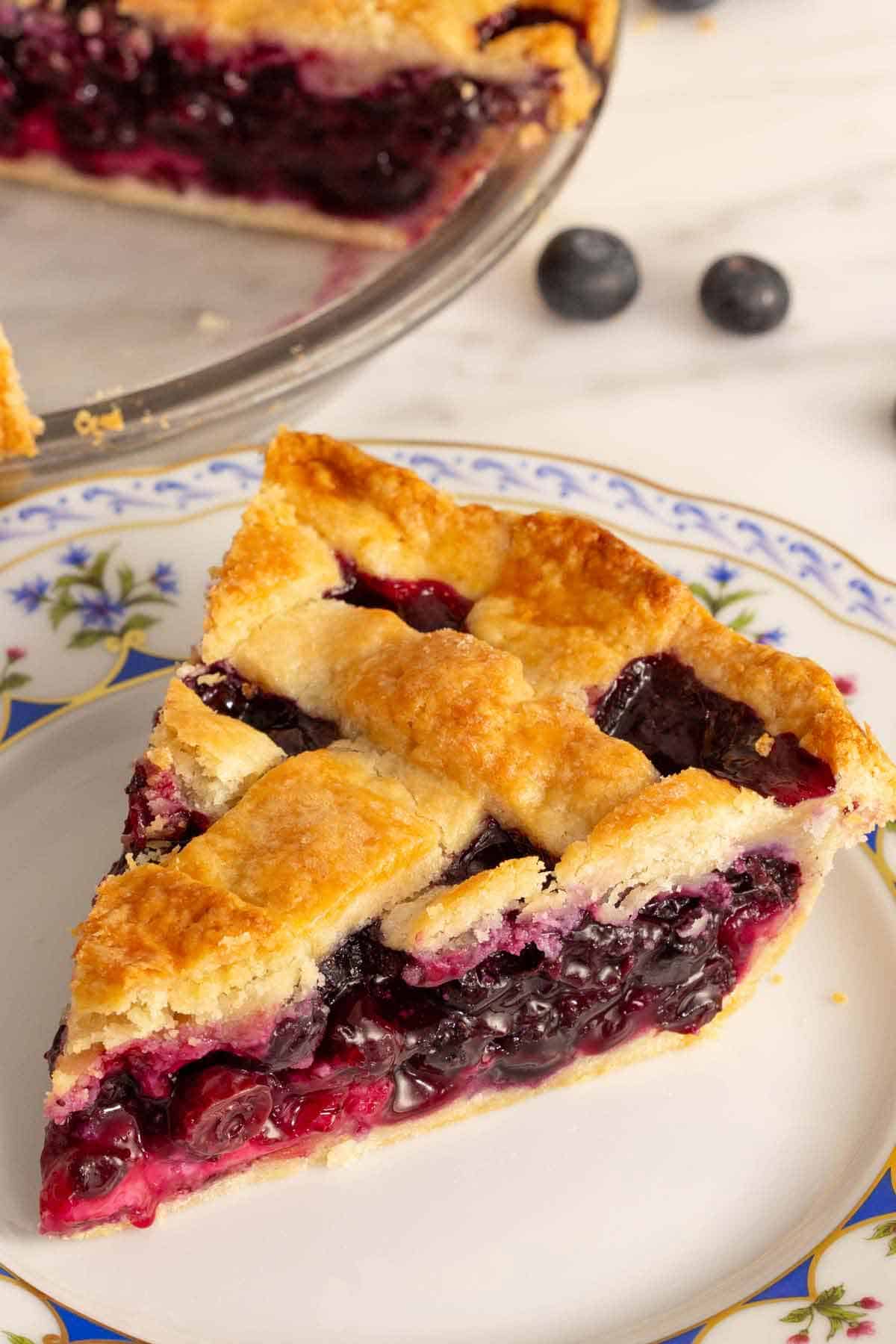 A close up view of a slice of blueberry pie on a plate.