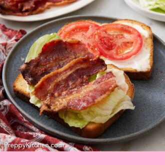 Pinterest graphic of a plate with two slices of bread with mayo, sliced tomatoes, lettuce, and candied bacon. More toppings in the background.