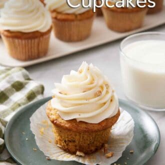 Pinterest graphic of a plate with a carrot cake cupcake with a glass of milk and platter of more cupcakes in the background.