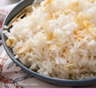 Pinterest graphic of a close up view of a bowl of coconut rice with a fork inside topped with toasted coconut.