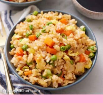 Pinterest graphic of a bowl of fried rice with a boy of sauce and another bowl of fried rice in the background.