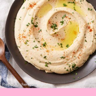 Pintrest graphic of an overhead view of hummus in a bowl, topped with oil, parsley, and paprika.