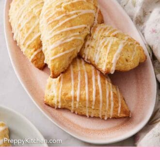 Pinterest graphic of a pink platter of lemon scones with a bowl of berries and a bowl of jam in the back.