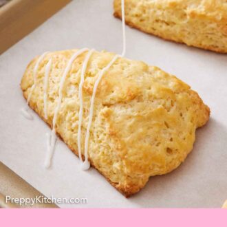 Pinterest graphic of icing drizzled over a lemon scone on a lined sheet pan.