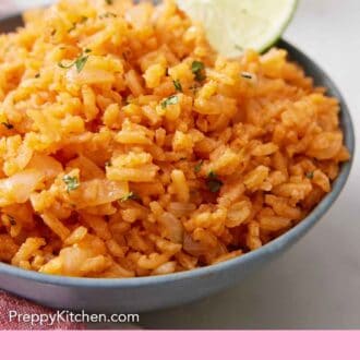 Pinterest graphic of a close up view of a bowl of Mexican rice with a lime inside.
