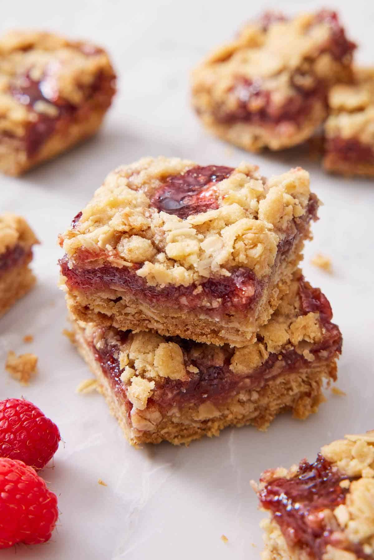 Two raspberry bars stacked on top of each other with more bars on scattered around.