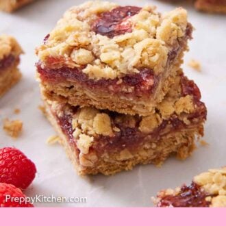 Pinterest graphic of two raspberry bars stacked on top of each other with more bars on scattered around.
