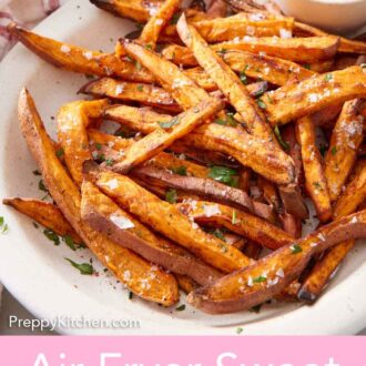 Pinterest graphic of a white platter of air fryer sweet potato fries garnished with parsley and flakey salt with a bowl of ketchup.