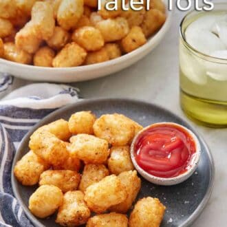 Pinterest graphic of a plate of air fryer tater tots with a bowl of ketchup. A drink in the background along with a large bowl of more tater tots.