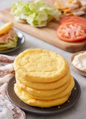 A plate with a stack of five cloud bread with sandwich fillings in the background.