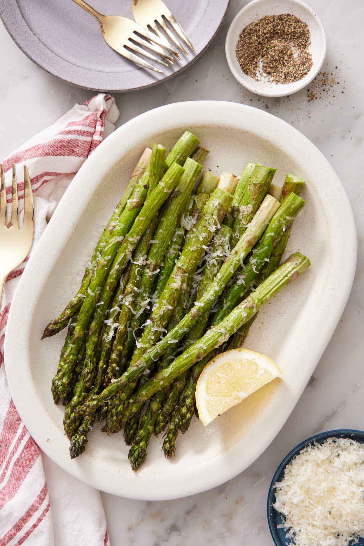 Overhead view of a platter of air fryer asparagus with a lemon wedge.