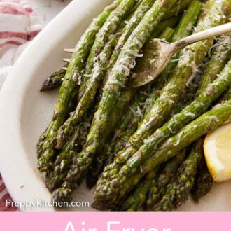 Pinterest graphic of a fork lifting up asparagus in a platter of air fryer asparagus with a lemon wedge.