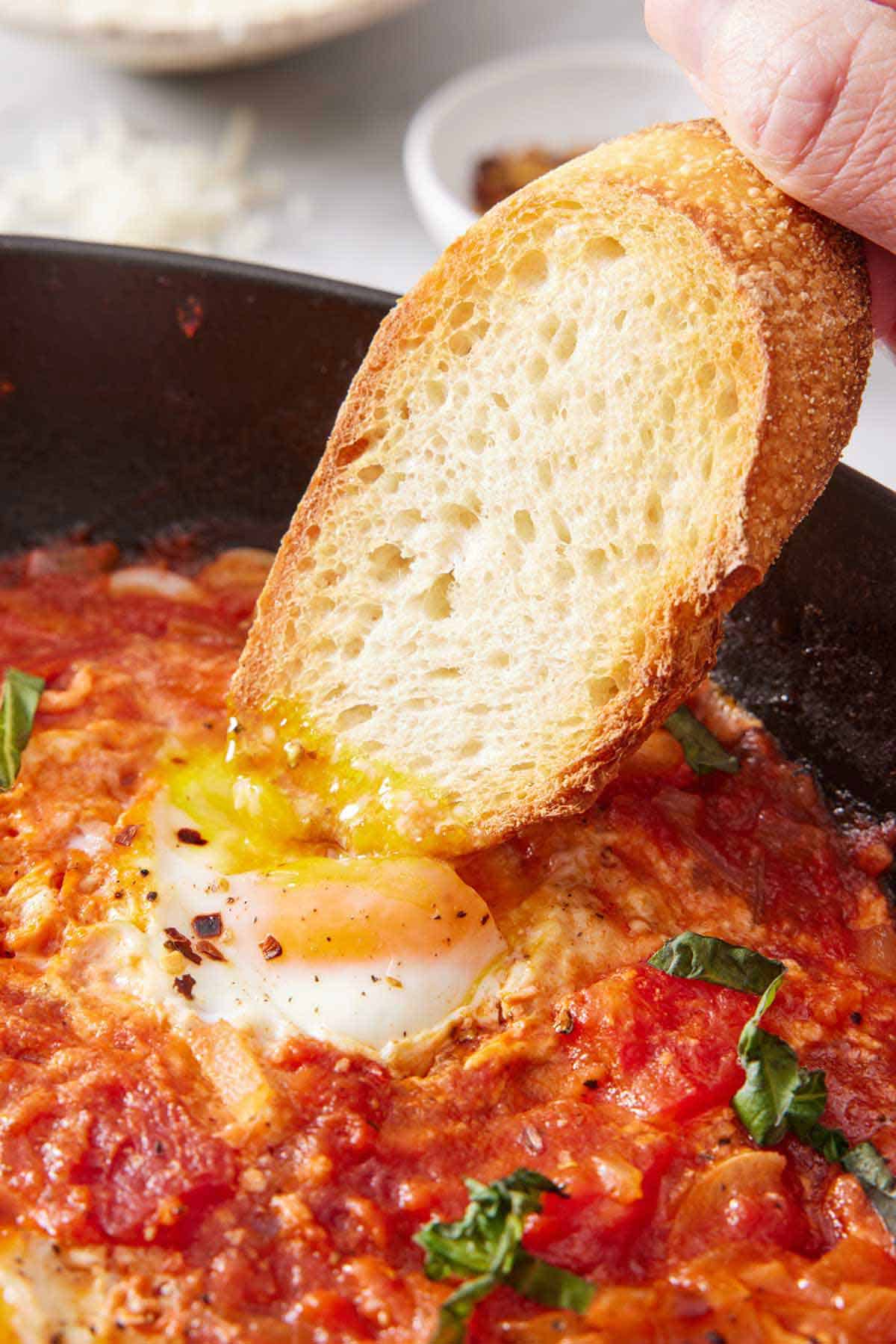 A piece of bread dipped into an egg yolk in a skillet of eggs in purgatory.