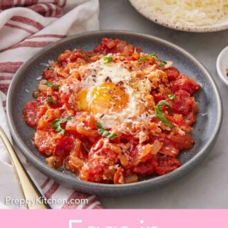 Pinterest graphic of a plate of eggs in purgatory with a plate of shredded cheese in the background.