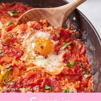 Pinterest graphic of a spoon scooping up eggs in purgatory in a skillet. Bowl of red pepper flakes in the background.