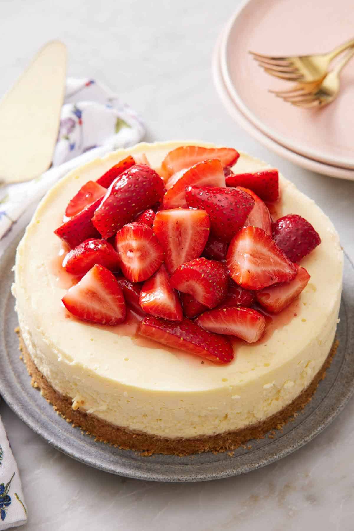 A plate with an Instant Pot cheesecake topped with fresh, chopped strawberries.