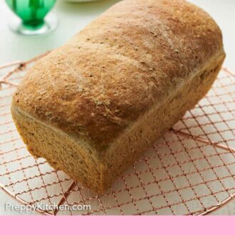 Pinterest graphic of a loaf of rye bread on a wire cooling rack.