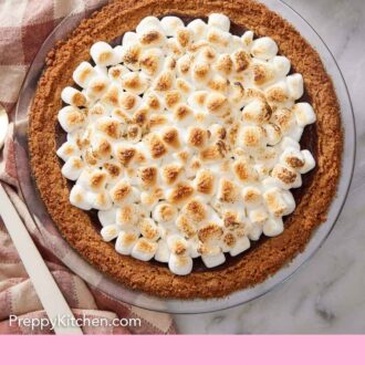 Pinterest graphic of a s'more pie with a stack of plates and forks off to the side.