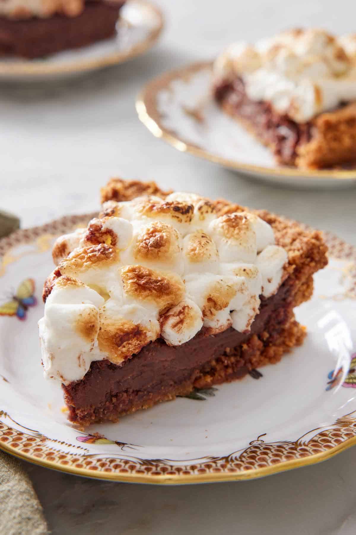 A plate with a slice of s'more pie with another in the background.