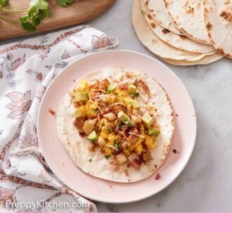 Pinterest graphic of an overhead view of a plate with a breakfast taco with an assortment of toppings beside it.