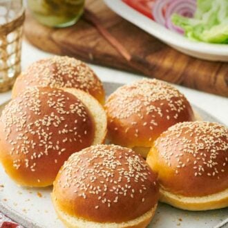 Pinterest graphic of a platter with multiple burger buns. Toppings in the background.