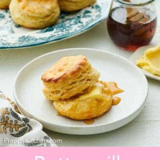 Pinterest graphic of a plate with buttermilk biscuits with some honey and butter. A plate of more biscuits and jar of honey in the back.