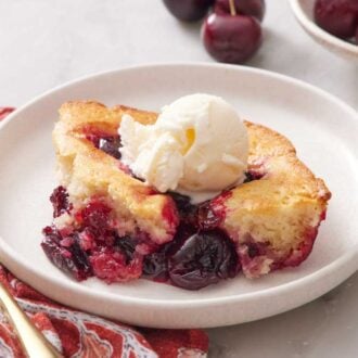 A plate with a serving of cherry cobbler with a scoop of ice cream on top.