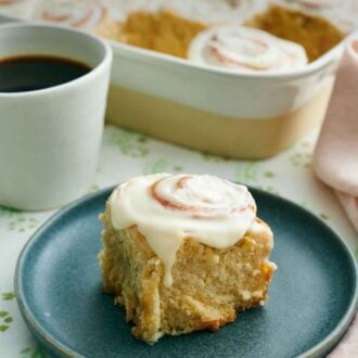 Pinterest graphic of a plate with a cinnamon roll. A baking dish with more rolls and a mug of coffee in the back.