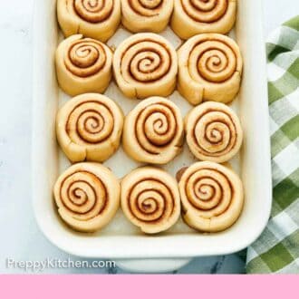Pinterest graphic of cinnamon rolls in a baking dish before baking.
