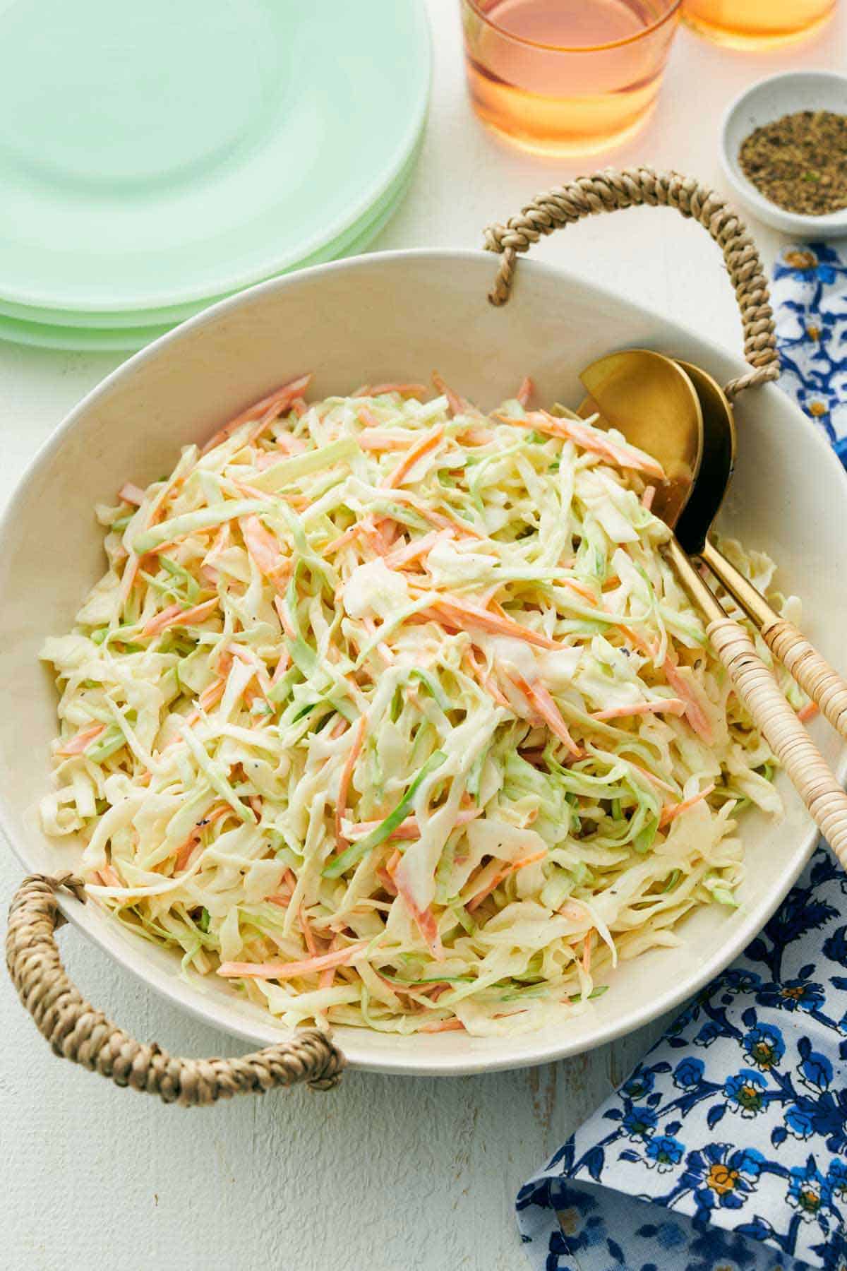Overhead view of a serving plate of coleslaw with serving spoons tucked in.