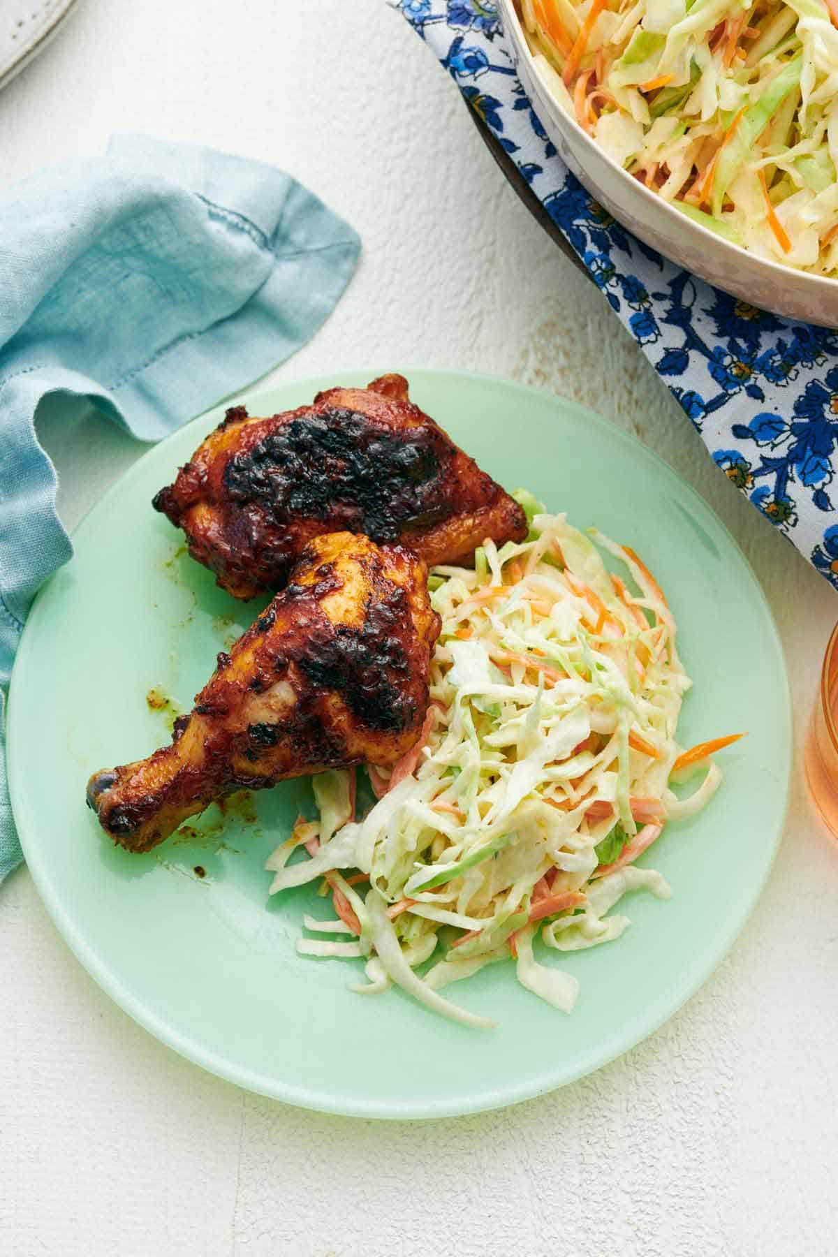 Overhead view of a plate of grilled chicken and coleslaw.
