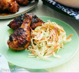 Pinterest graphic of a plate with coleslaw and grilled chicken drumsticks. More chicken and coleslaw in the background.