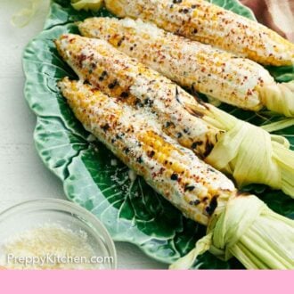 Pinterest graphic of a platter of elote with a bowl of cotija cheese in front.