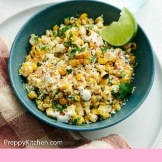 Pinterest graphic of bowl of elote corn topped with cilantro with a lime wedge.