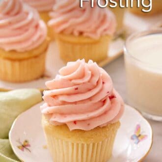 Pinterest graphic of a cupcake topped with strawberry frosting with more topped cupcakes in the background along with a glass of milk.