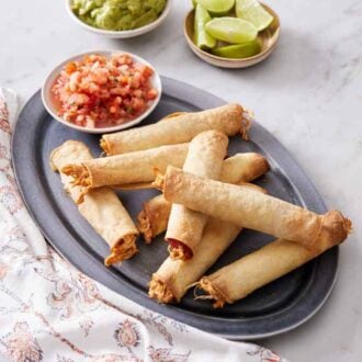 A platter of air fryer taquitos with a bowl of salsa.