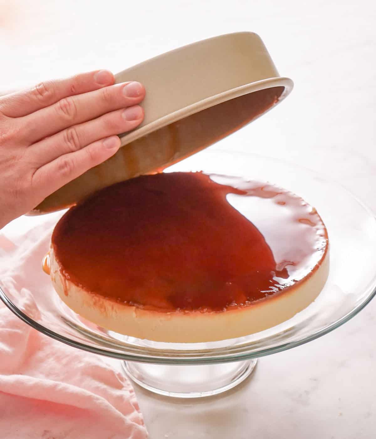 A flan being poured from the baking dish onto the cake stand.